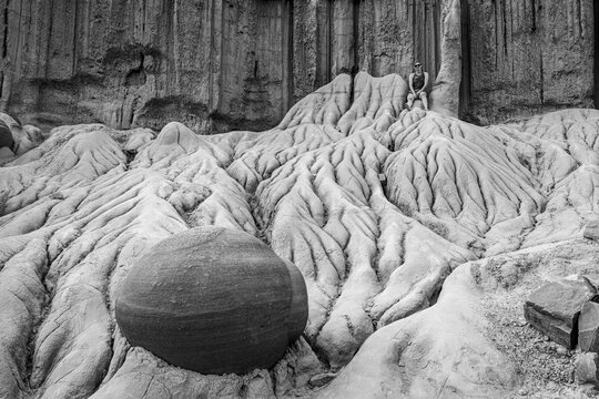 Woman sits atop surreal desert rock formations