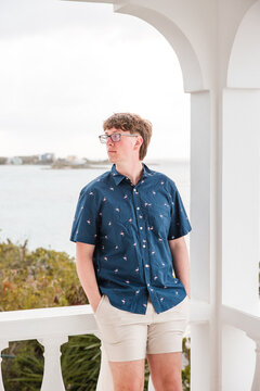 Young man looks out from a white balcony