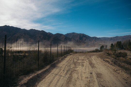 Dusty dirt road leading to arid mountains