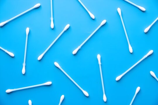 Flat lay overhead view of multiple cotton swabs arranged on a vibrant blue background