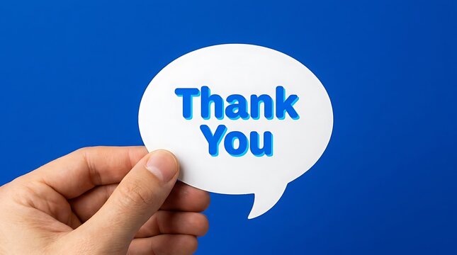 Human hand holding a white speech bubble cutout with blue thank you text against a solid blue