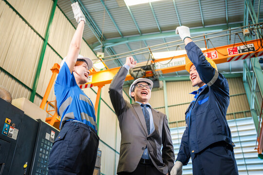 industrial team celebrating success in manufacturing factory, factory workers and manager cheering for achievement in workshop, confident industrial team in safety gear celebrating production goal