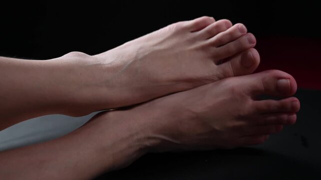 Foot fetish. Close-ups of naked female feet with silver chain jewelry.
