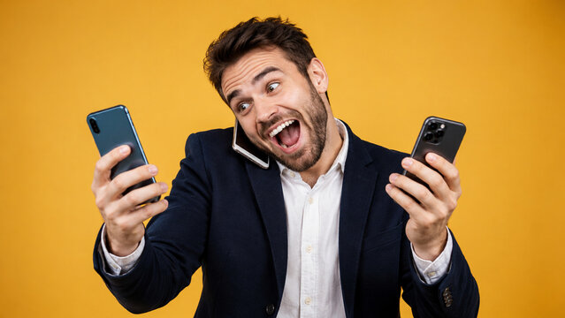 Excited businessman talking and holding multiple smartphones over yellow background.