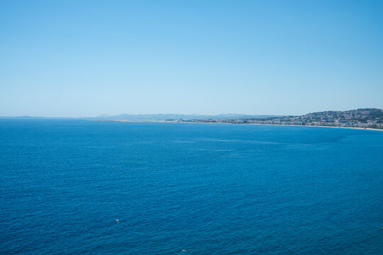 A vast expanse of deep blue Mediterranean Sea with the Nice coastline and distant mountains under a clear sky