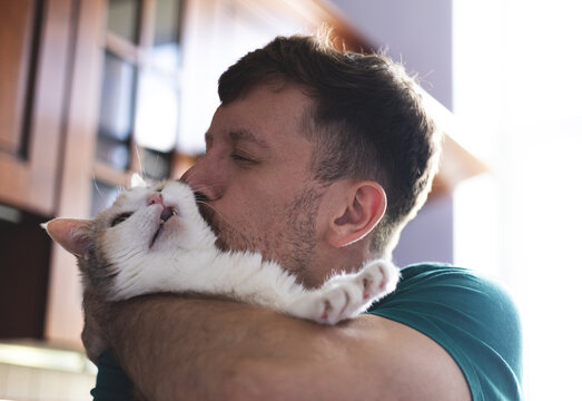 A young man hugs a cat