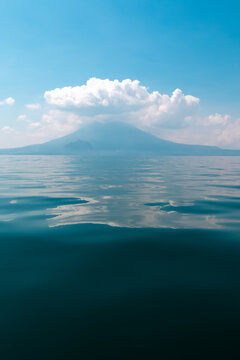 Calm lake and distant volcano under blue sky