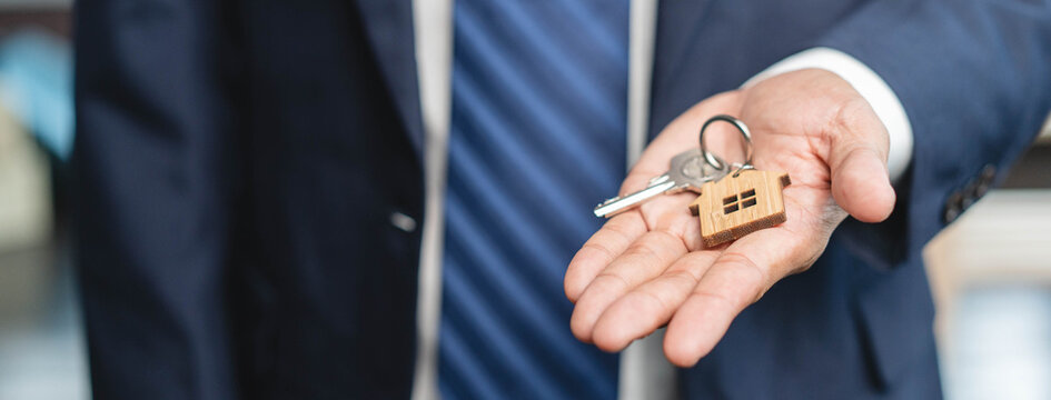 Close up view realtor broker holding home keychain in his hand.