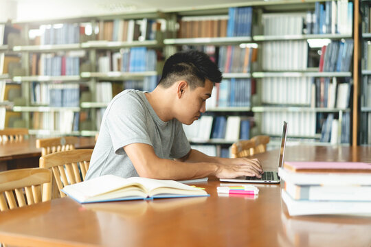 male asian student studying and reading book in library