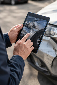 Insurance professional documenting vehicle damage with a tablet after a car accident, illustrating digital claims processing, collision assessment, repair estimation and auto insurance services