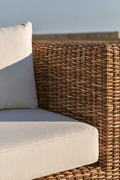 Closeup of woven rattan chair texture with cream cushion on urban rooftop, afternoon light highlighting the intricate weave and design