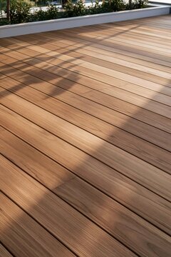 Closeup of warm teak decking texture on urban rooftop, golden hour light illuminating grain with planter shadow across the surface