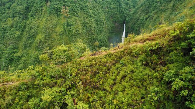 Woman exploring lush mountain trail and waterfall in rainforest of Costa Rica