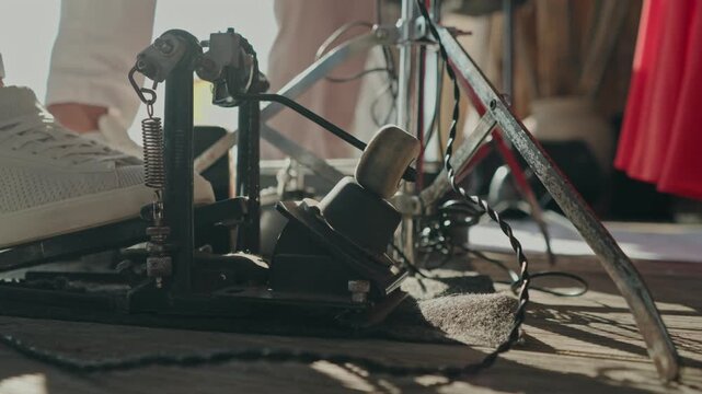 Kick pedal beater and hardware on a wooden stage floor with band members behind