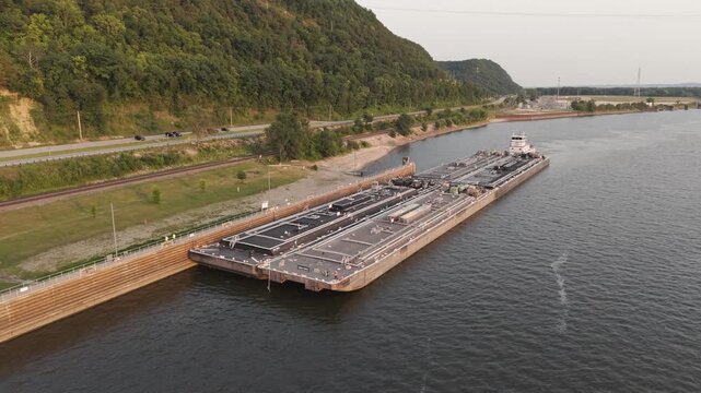 Between Wisconsin and Iowa on the Mississippi River, a towboat and fuel barges approach the US Lock and Dam number 8.