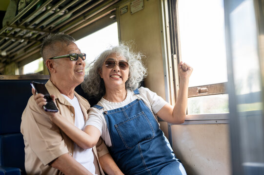 Asian senior couple taking a selfie together during a train journey