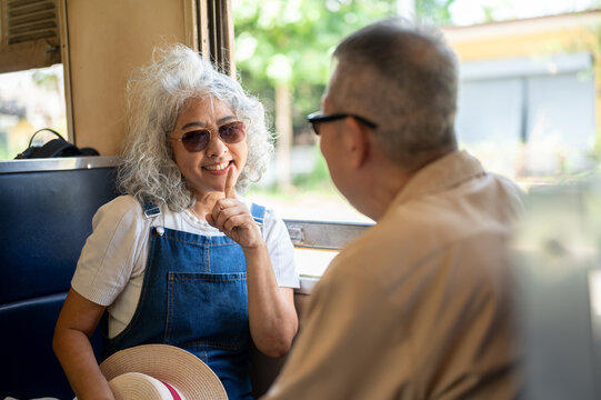 Asian senior elderly couple sharing a relaxed conversation during their vintage train adventure.