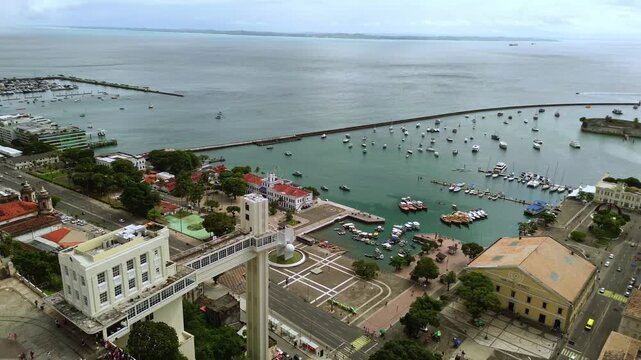 Aerial drone orbit revealing the Lacerda Elevator historic Mercado Modelo and boats in the beautiful Todos os Santos Bay in Salvador Bahia Brazil