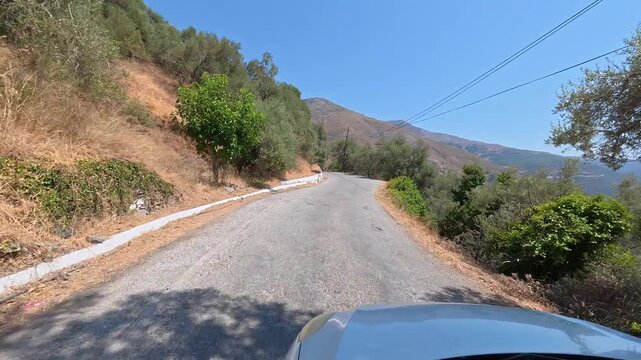White car driving slowly on a narrow dangerous mountain road on the island of Crete, Greece