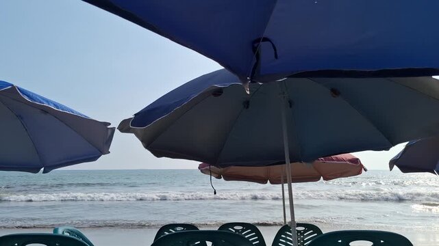 Blue Beach Umbrellas and Ocean Waves on Sandy Seashore for Tropical Summer Vacation and Tourism Concept