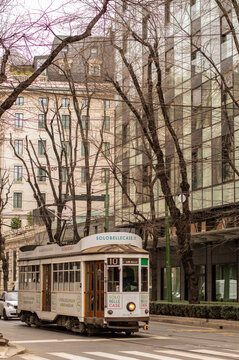 Milan, Italy - January 16 2019: Historic tram travels along a city street in central Milan, surrounded by modern and traditional architecture. Vintage public transport operating on tram route 10.