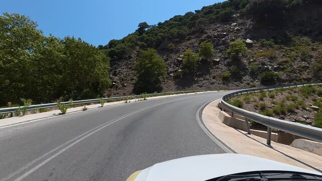 White car driving slowly on a narrow dangerous mountain road on the island of Crete, Greece