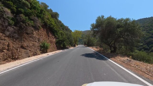 White car driving slowly on a narrow dangerous mountain road on the island of Crete, Greece