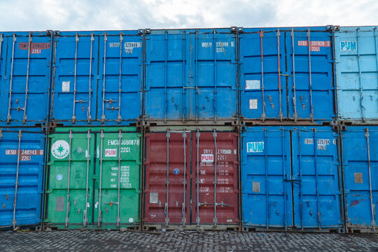 Jakarta, Indonesia - August 21, 2026: Stacked blue, green, and red shipping containers at a port terminal, illustrating cargo storage, maritime logistics, and international trade.