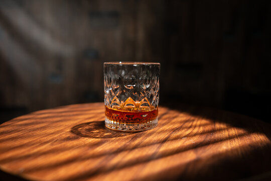 Crystal Glass of Whiskey on Wooden Table with Sunlight Shadows