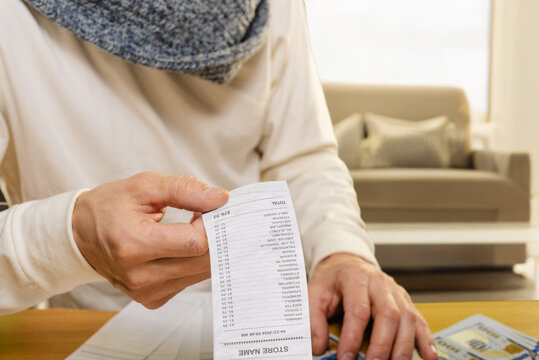 Closeup photo of man managing household expenses with receipts and bills Checking itemized grocery receipts to understand daily spending habits and control the household budget