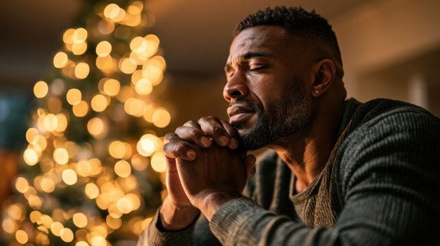 Black Man Praying Beside Glowing Christmas Tree