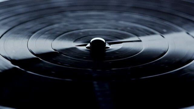 Close-up view of a vinyl record spinning on a turntable, showcasing the smooth surface and central spindle as it rotates in a dimly lit environment