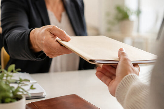 Business professionals exchanging documents during a formal meeting, representing contract review, paperwork submission, business agreement, administration and professional document management