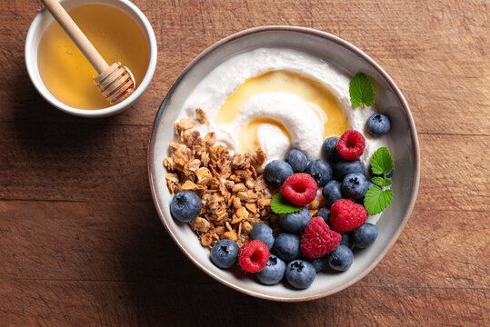 Granola bowl with greek yogurt, berries and honey for healthy breakfast.