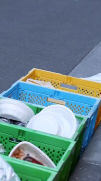 Person Throwing Trash into Plastic Recycling Crates on Tokyo Sidewalk