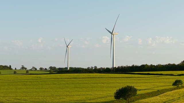 Green electricity flowing from wind energy systems above rural fields. Renewable power generation supporting environmental sustainability and clean technology. Wind turbines driving energy transition