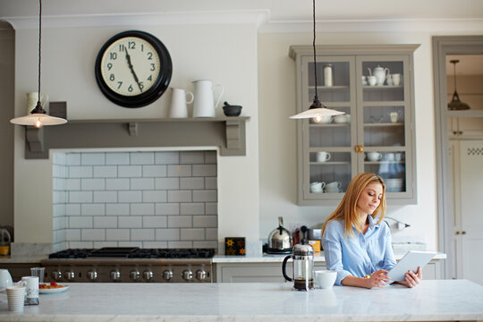 Smile, woman and coffee at house with tablet, social media and browsing online for latest movies. Person, rest and breakfast in kitchen with digital, internet search and streaming for film watchlist