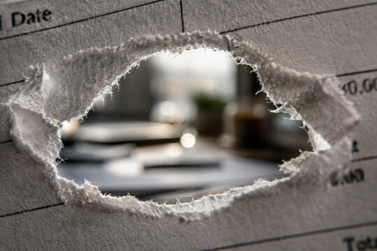 Torn paper calendar with a large irregular hole revealing a blurred background, symbolizing change, disruption and passing time