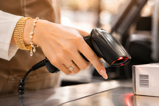 Close-up of a retail worker using a handheld barcode scanner to process a product at a store checkout