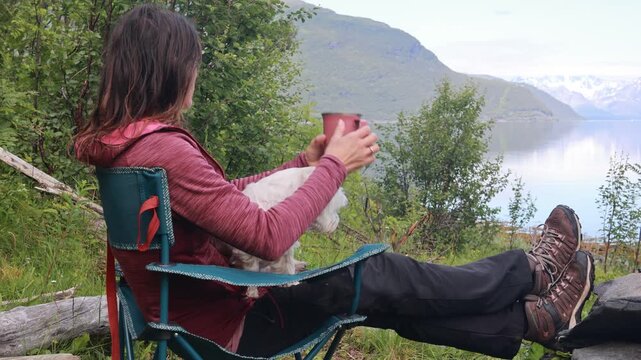 Woman, drinking coffee in the morning in front of a tent, wild camping in nature, Norway, morning, sunny morning