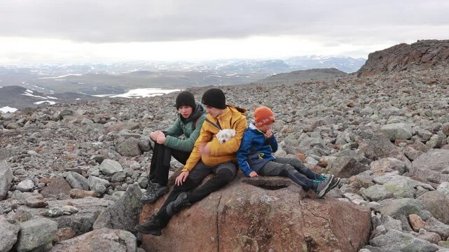 European family with children and pet dog, hiking Halti, the highest peak in Finland, child with pet dog, backpacking, summer, trail, snow, bad weather