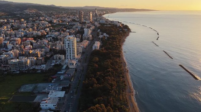 Aerial view of Limassol cityscape and coastline during sunset with drone motion.