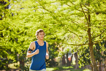Workout, man and running with earphones at park for morning cardio, fitness podcast and wellness....