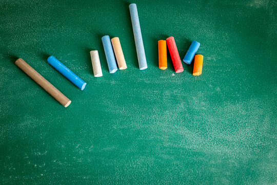 Colorful Chalk Pieces on Green Chalkboard with Copy Space