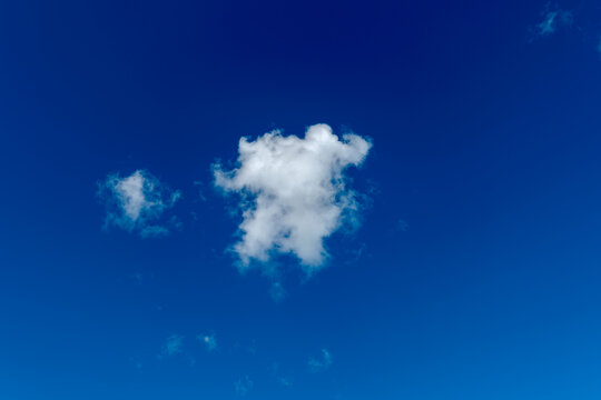 Small White Cumulus Cloud Floating in Vast Deep Blue Sky