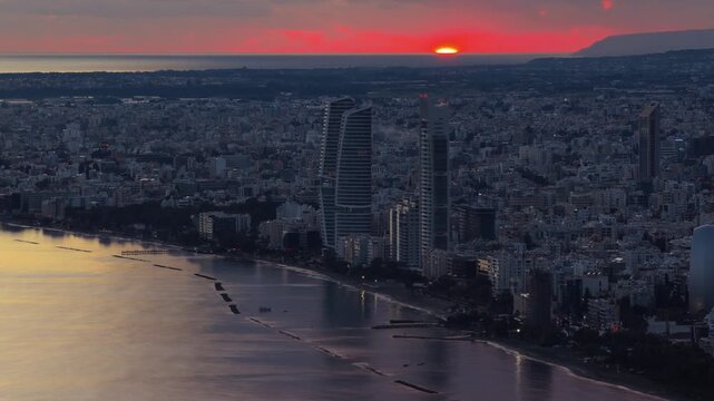 A mesmerizing aerial time-lapse captures the stunning sunset over limassol city with vibrant red hues painting the sky and a dynamic play of clouds creating a dramatic backdrop as the sun 