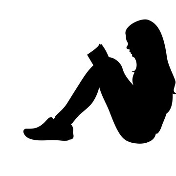A young woman sits with her knees drawn up while reading a book
