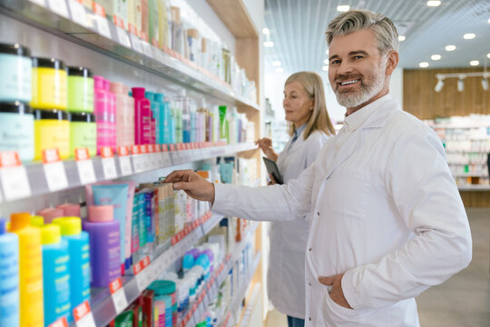 Two colleagues working in the pharmacy and putting the pills on the shelves