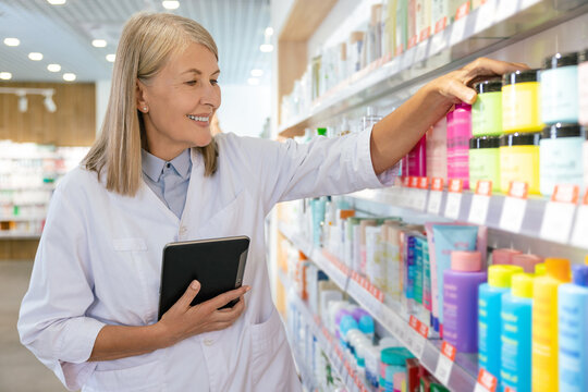 Two colleagues working in the pharmacy and putting the pills on the shelves
