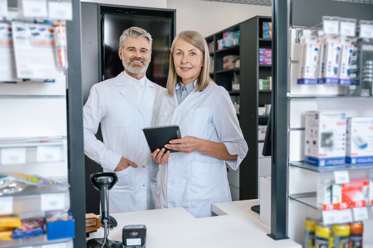 Man and woman in lab coats working together in the pharmacy